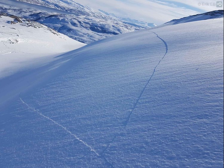 Bilde av snødekket som har lange sprekker i seg.