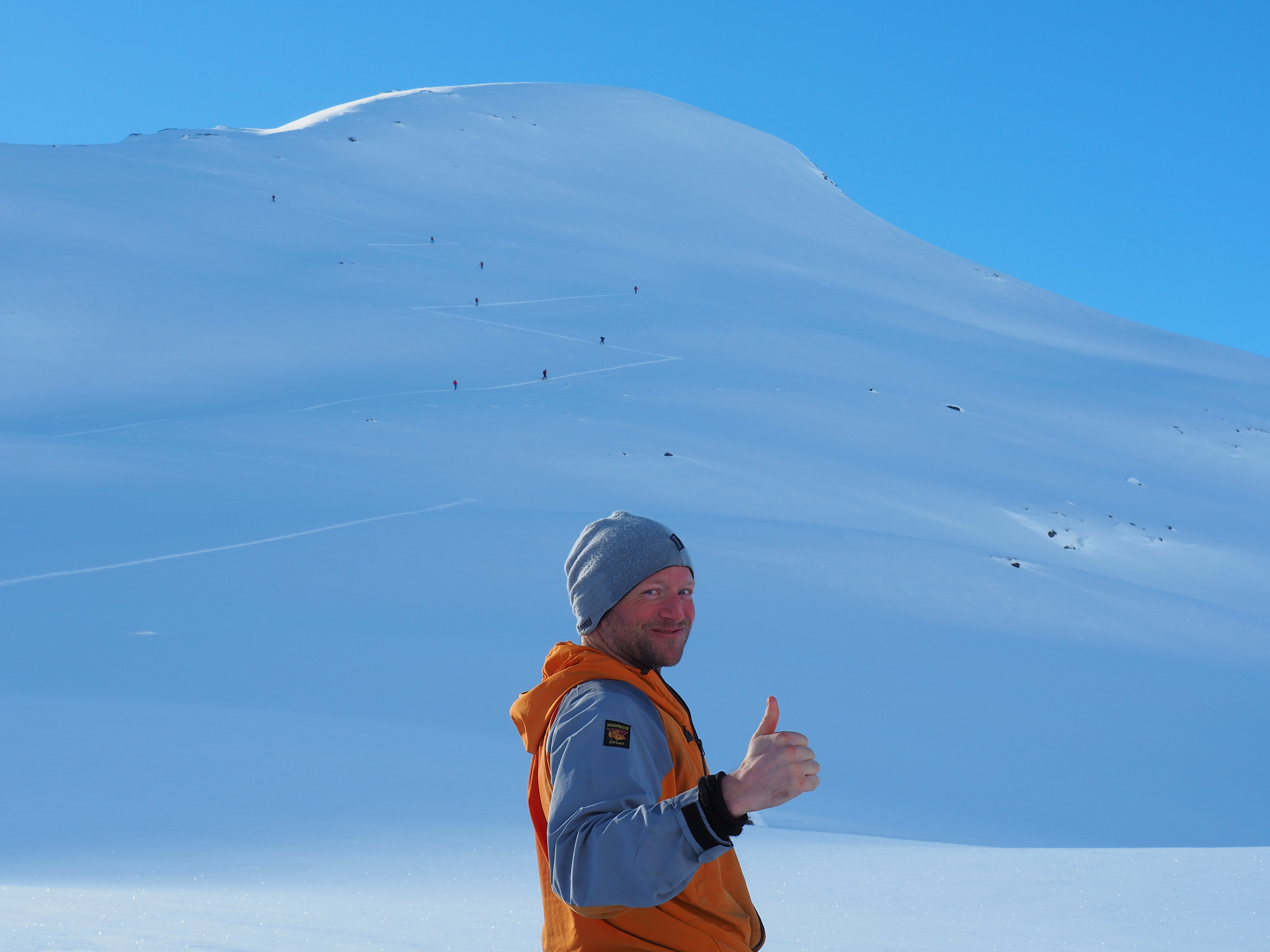 En person gir tommel opp for god avlastningsavstand innad grupper skigåere.