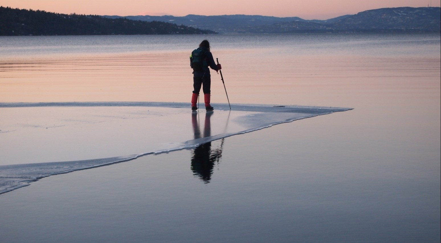 En person som står på kanten av islagt vann.
