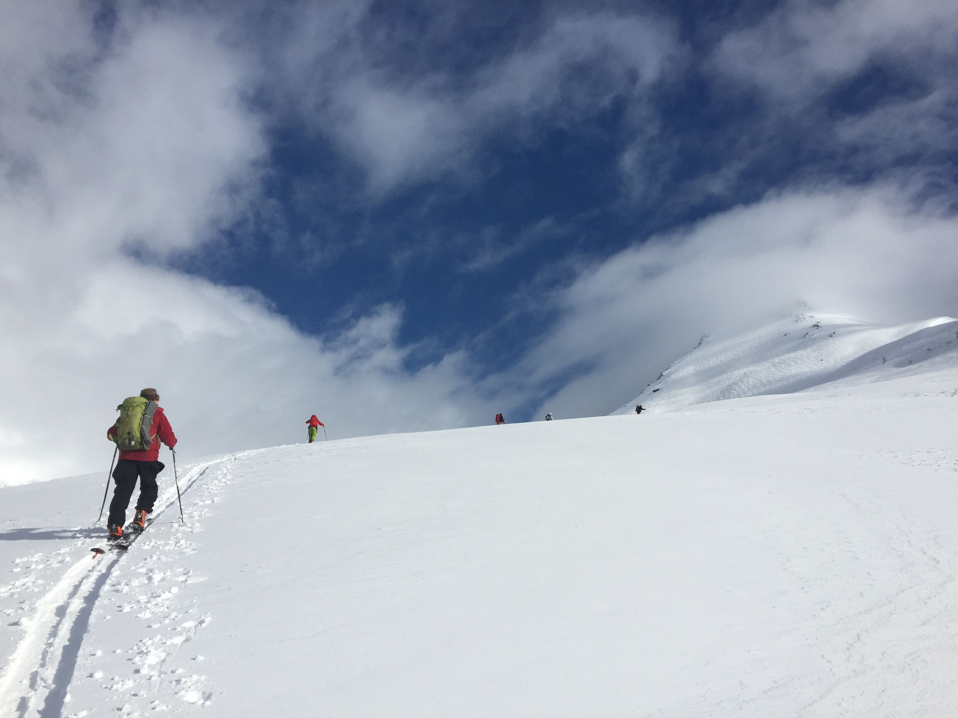 En gruppe skigåere beveger seg oppover en fjellside med god avlastningsavstand.
